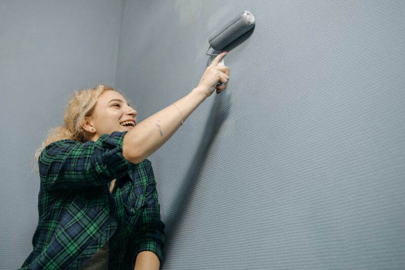 image - A smiling woman painting the walls grey.